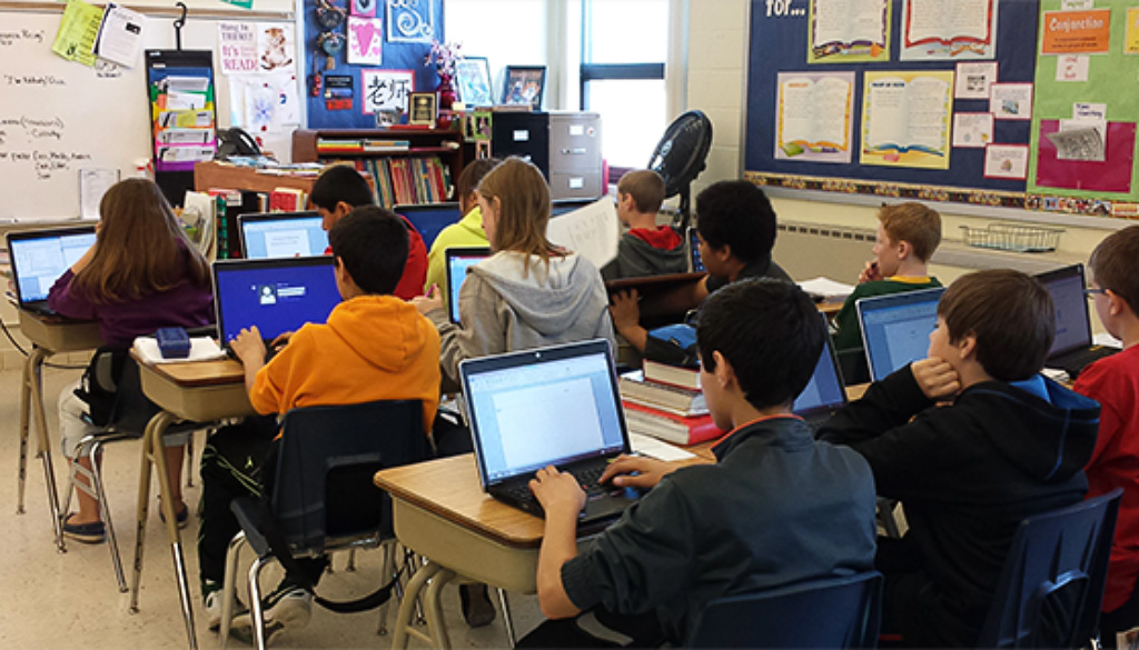 Elementary school students using laptops in a classroom.