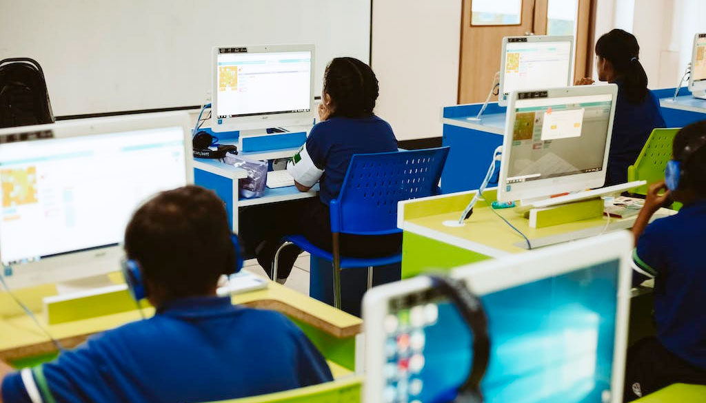 Elementary school children working on computers enabled with cybersecurity protections in a classroom.