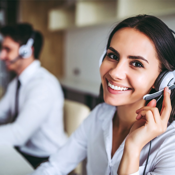 A help desk services employee smiles while answering a call from a customer.