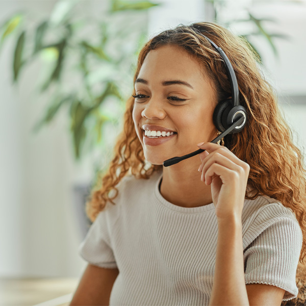 An IT service employee smiles while talking to a customer on a headset.