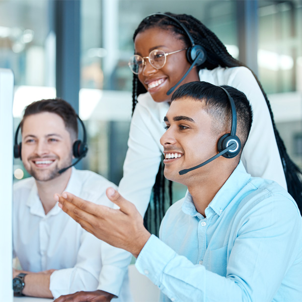 Smiling employees working in a customer support center wearing headsets.